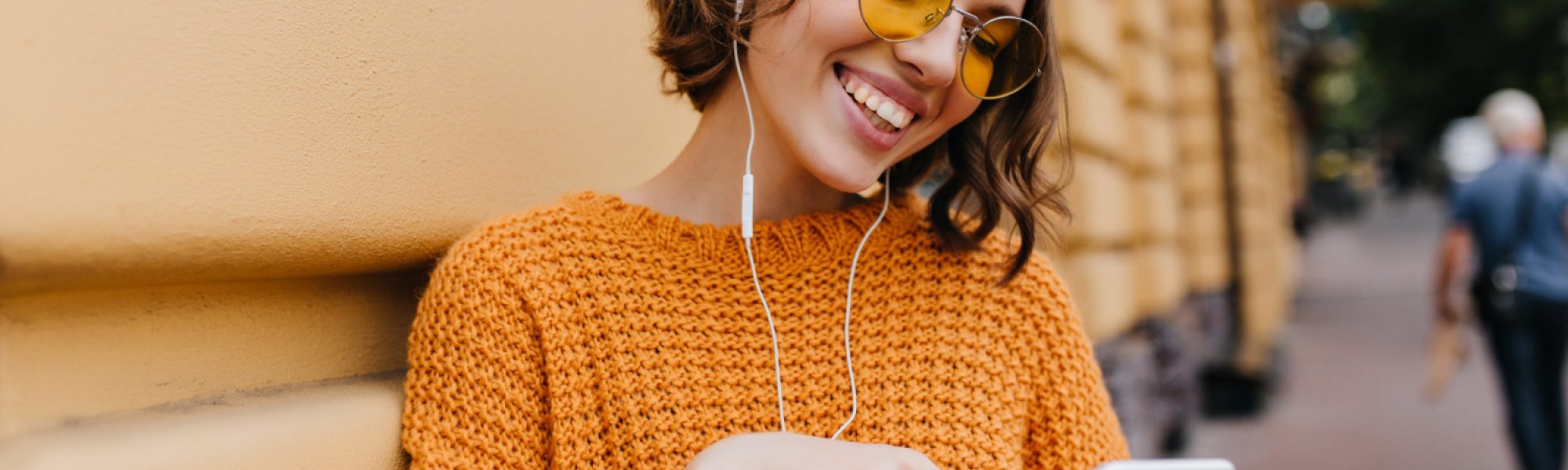 excited-young-woman-typing-message-standing-near-building-after-walk