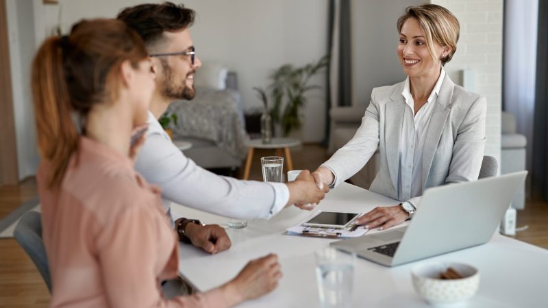 Happy real estate agent greeting a couple while having a meeting in the office.